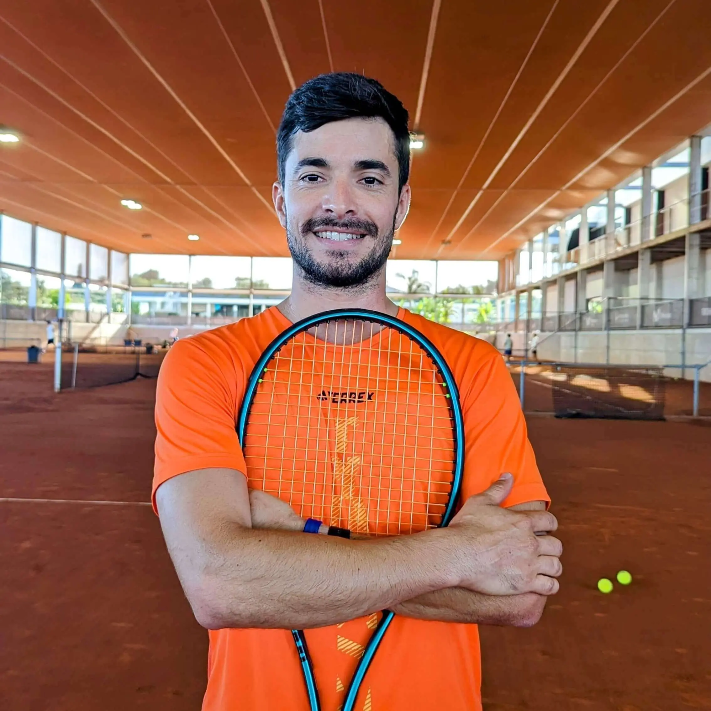 Headshot of the Evolve high performance tennis coach Javier Poblete with a tennis racket, symbolizing our commitment to science based tennis training and how to develop a tennis player effectively.