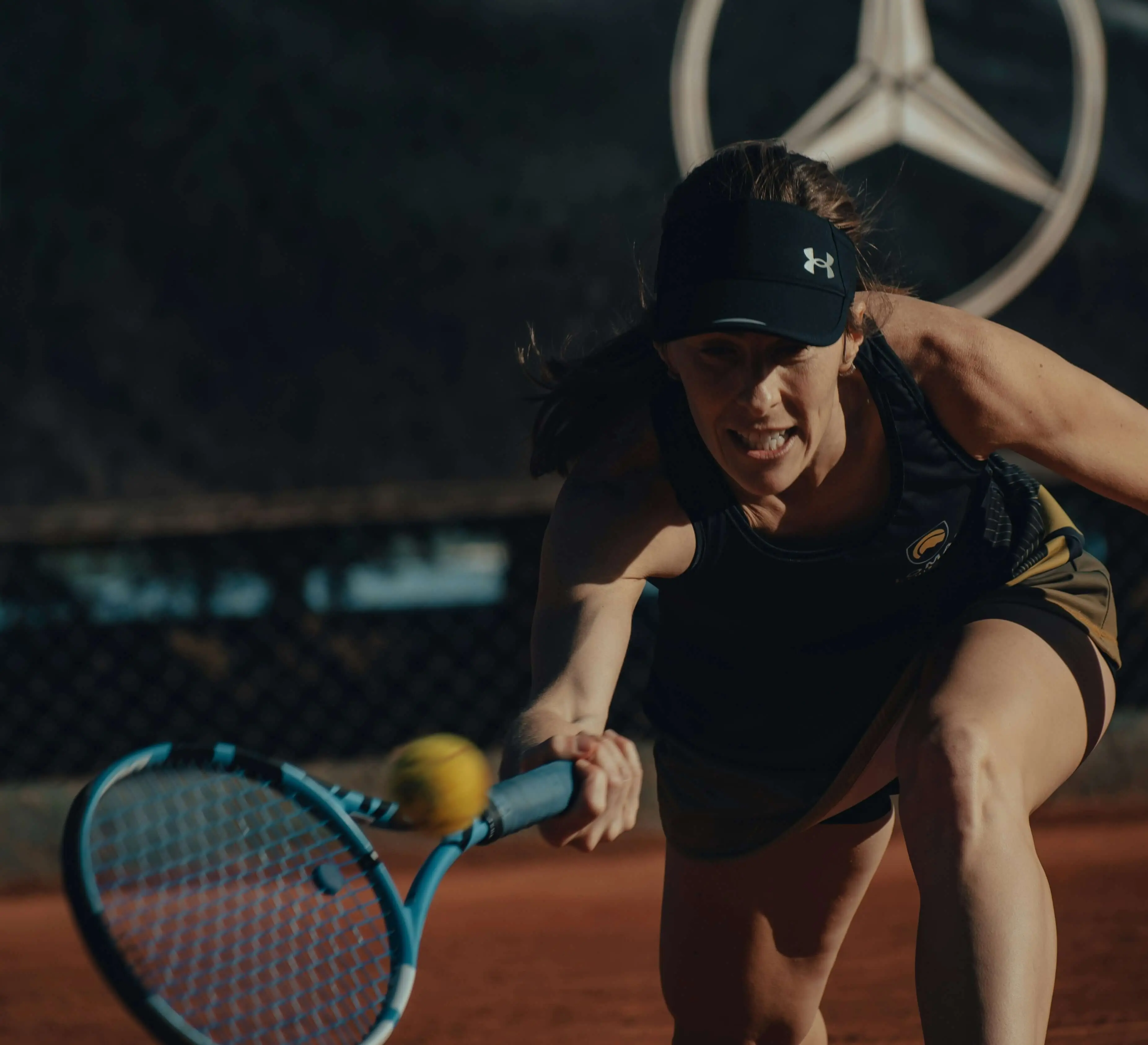 Tennis player reaching low for a shot on a clay court, highlighting the agility and movement developed through a tailored tennis fitness routine and full body tennis workout in our online tennis program.