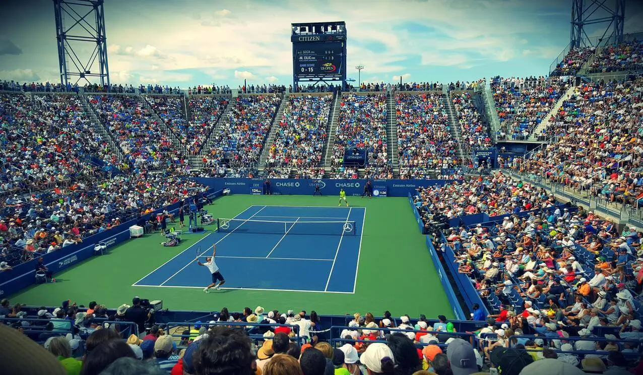 Wide view of a tennis match in a large stadium, representing the competitive goals achievable with a solid tennis development plan that includes tennis mental training and is supported by our online tennis program.