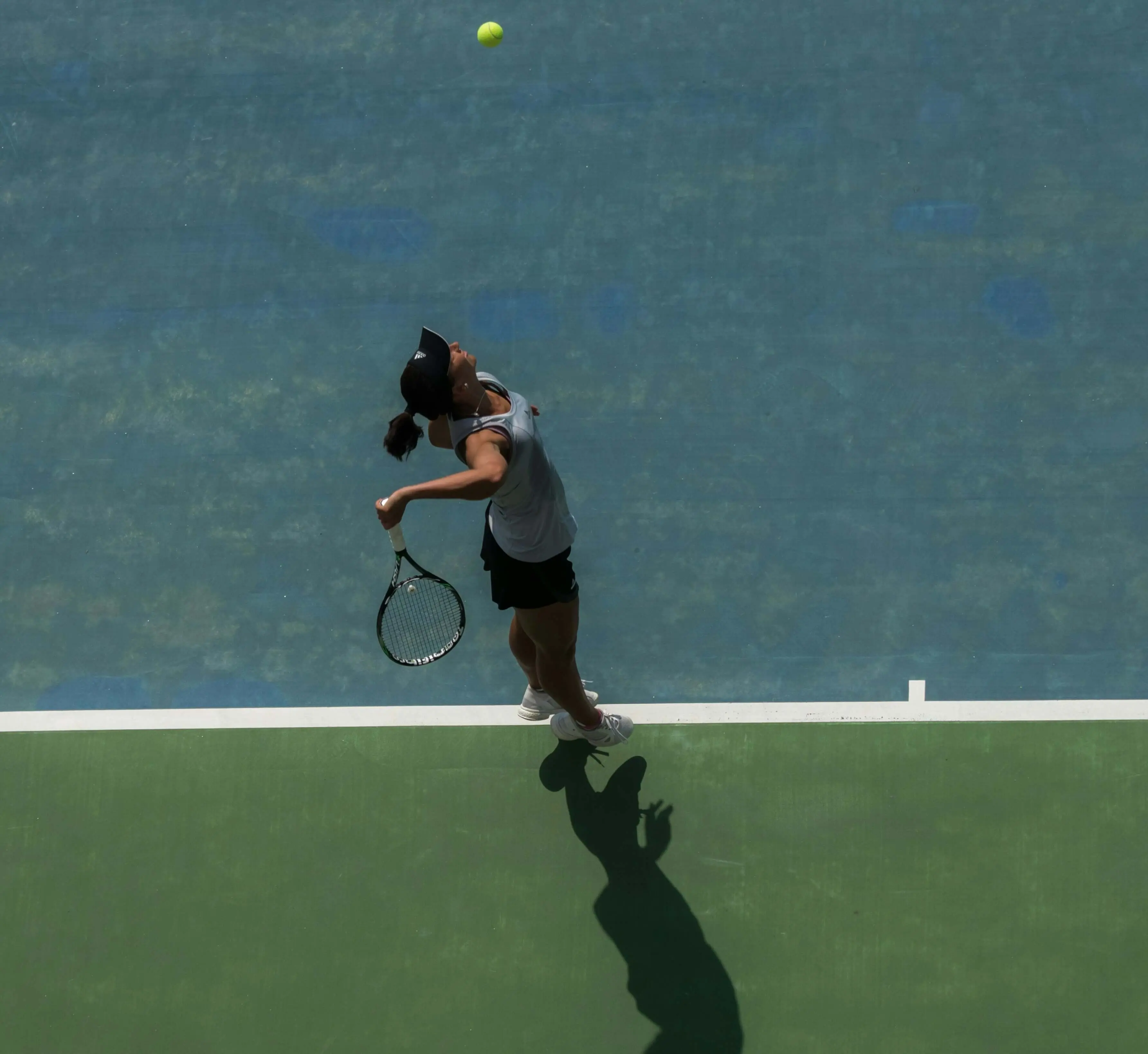 Overhead view of a tennis player in the motion of serving, depicting a key skill refined through Evolve's science based tennis training and personalized tennis player development plan.