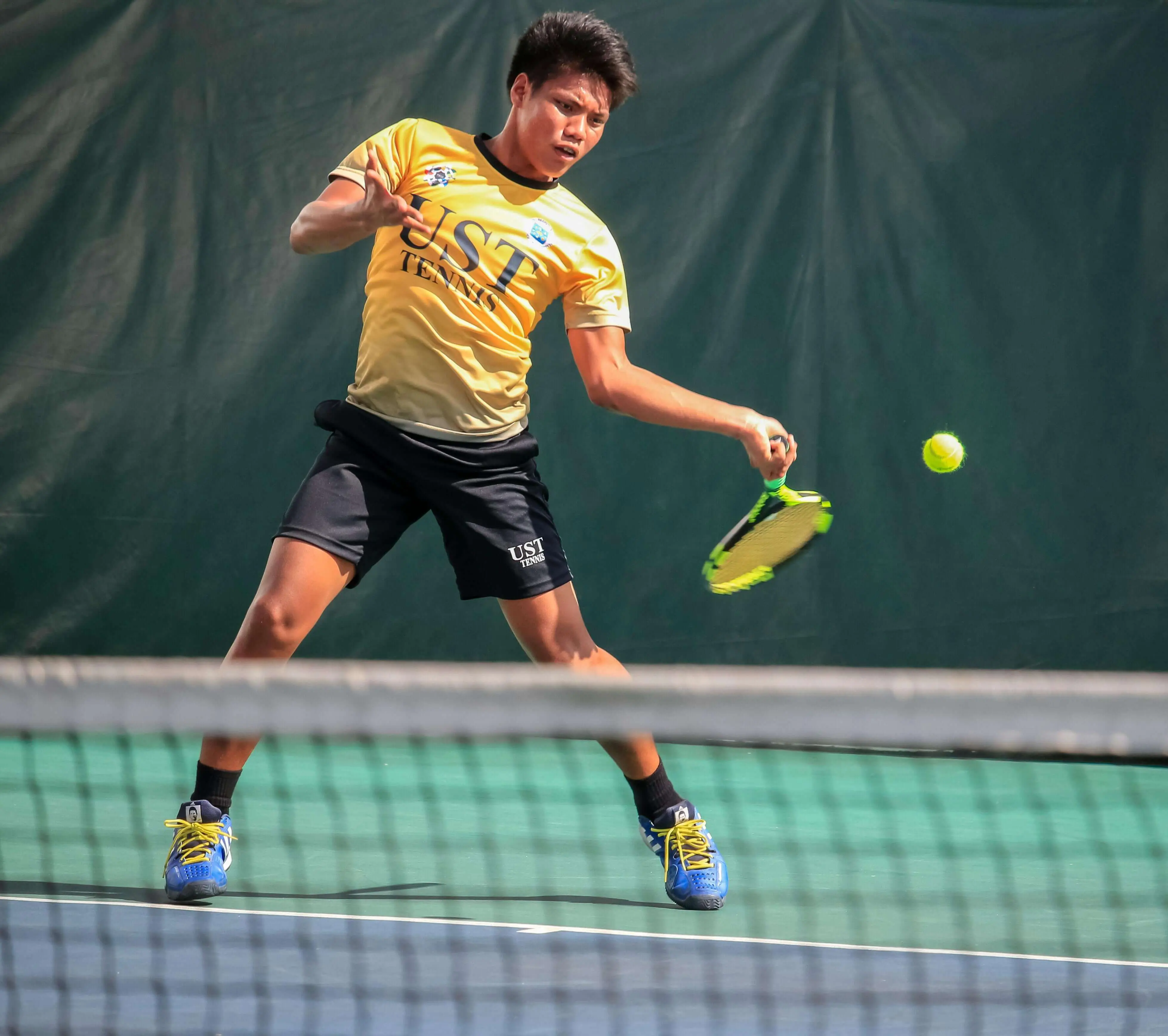 Young male tennis player hitting a forehand shot, illustrating Evolve's focus on tennis junior development and building a strong tennis player development plan.