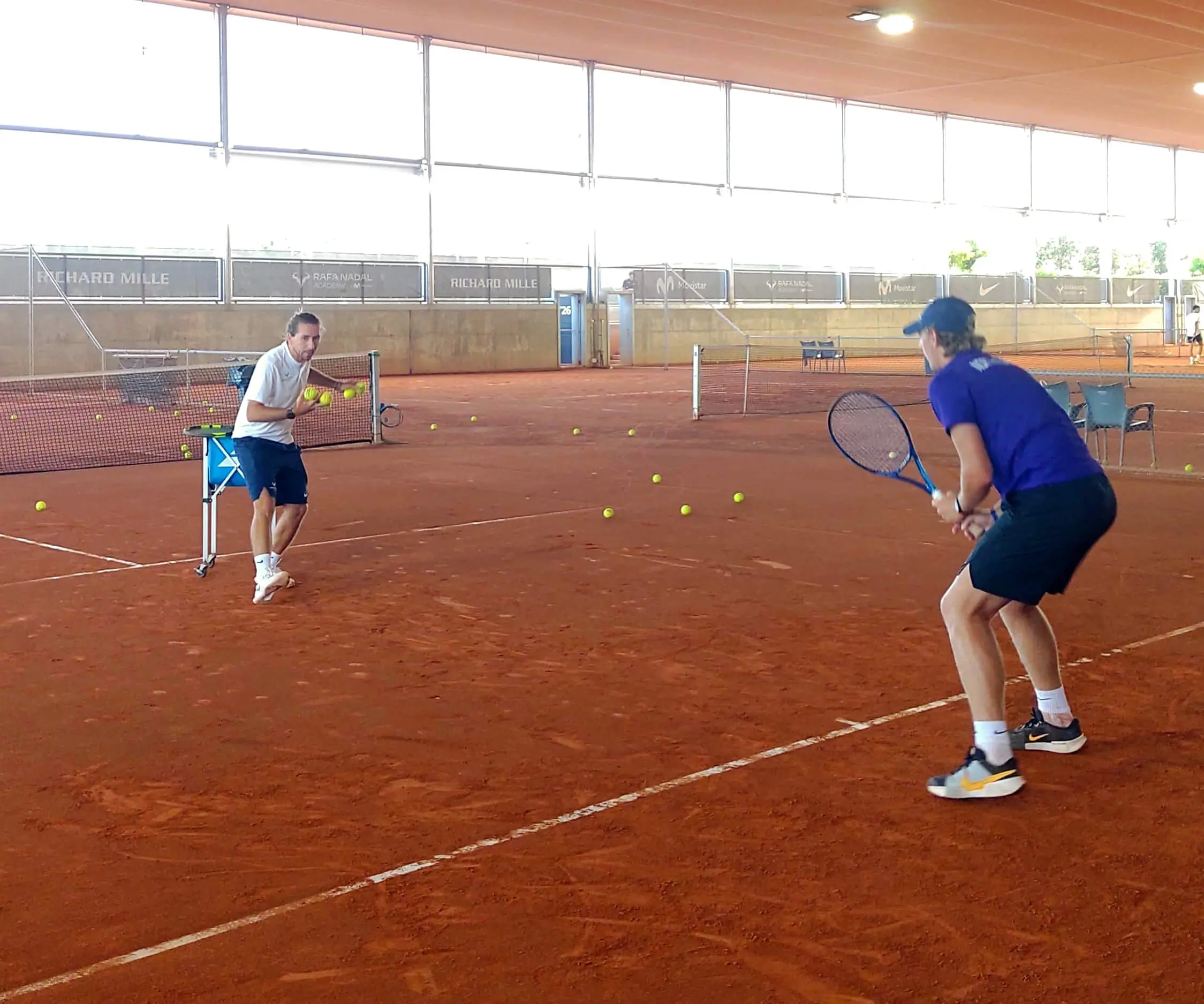 High Performance tennis coach Riccardo Leone working with a player on court, applying science based tennis training and potentially tennis cognitive training principles.
